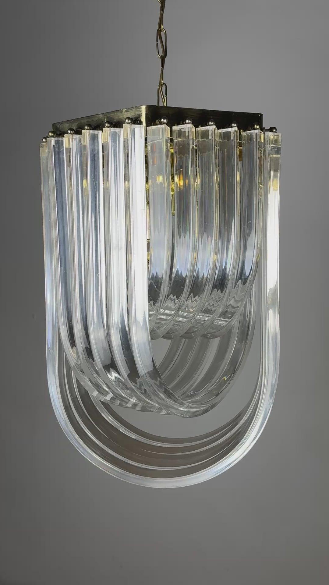 Load video: Long Mid-Century Curved Lucite Ribbon Chandelier in Brass, Italy